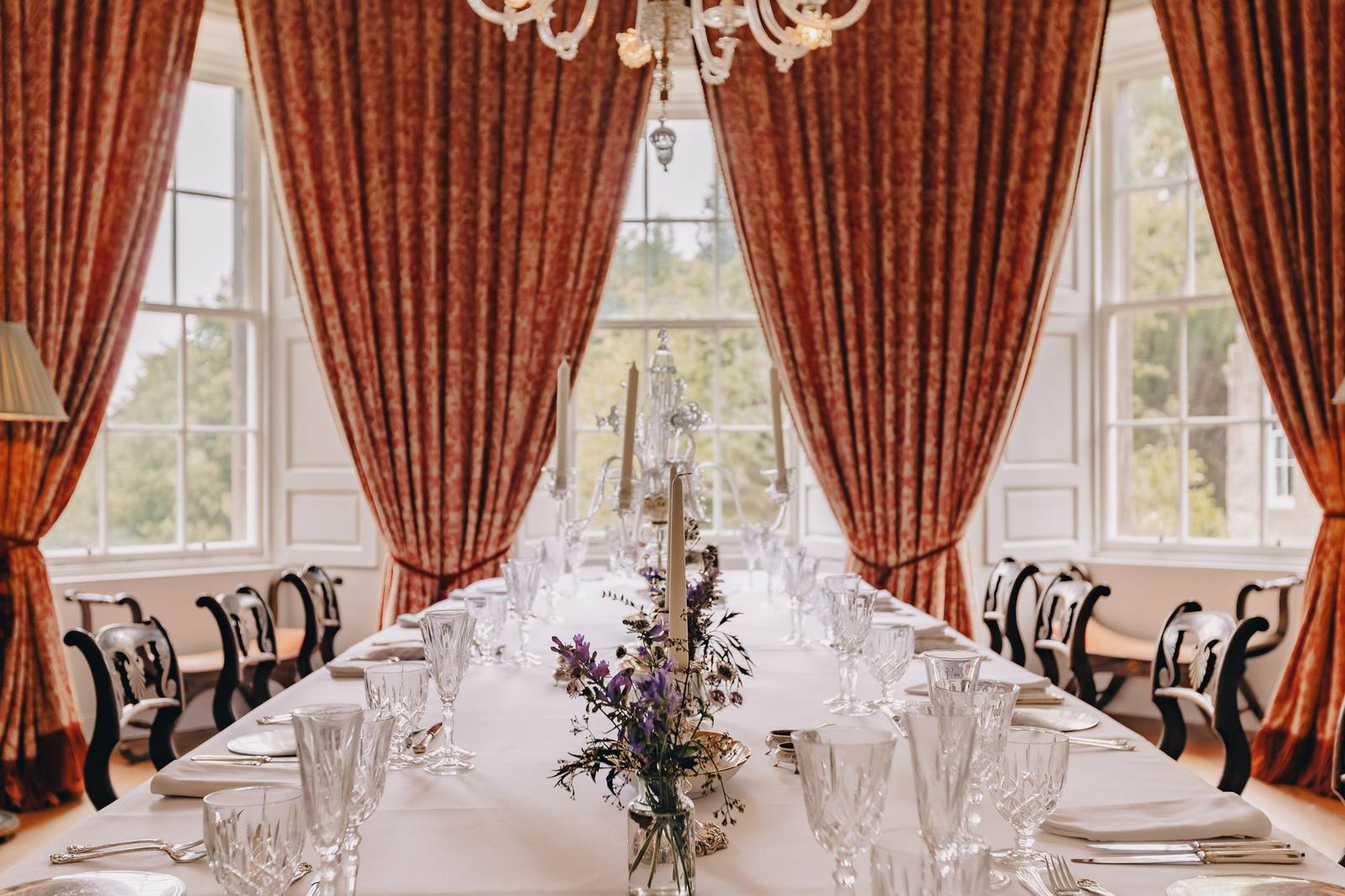 Formal dining room at Birkhill Castle with tartan-red curtains and silver candelabra, set for lunch