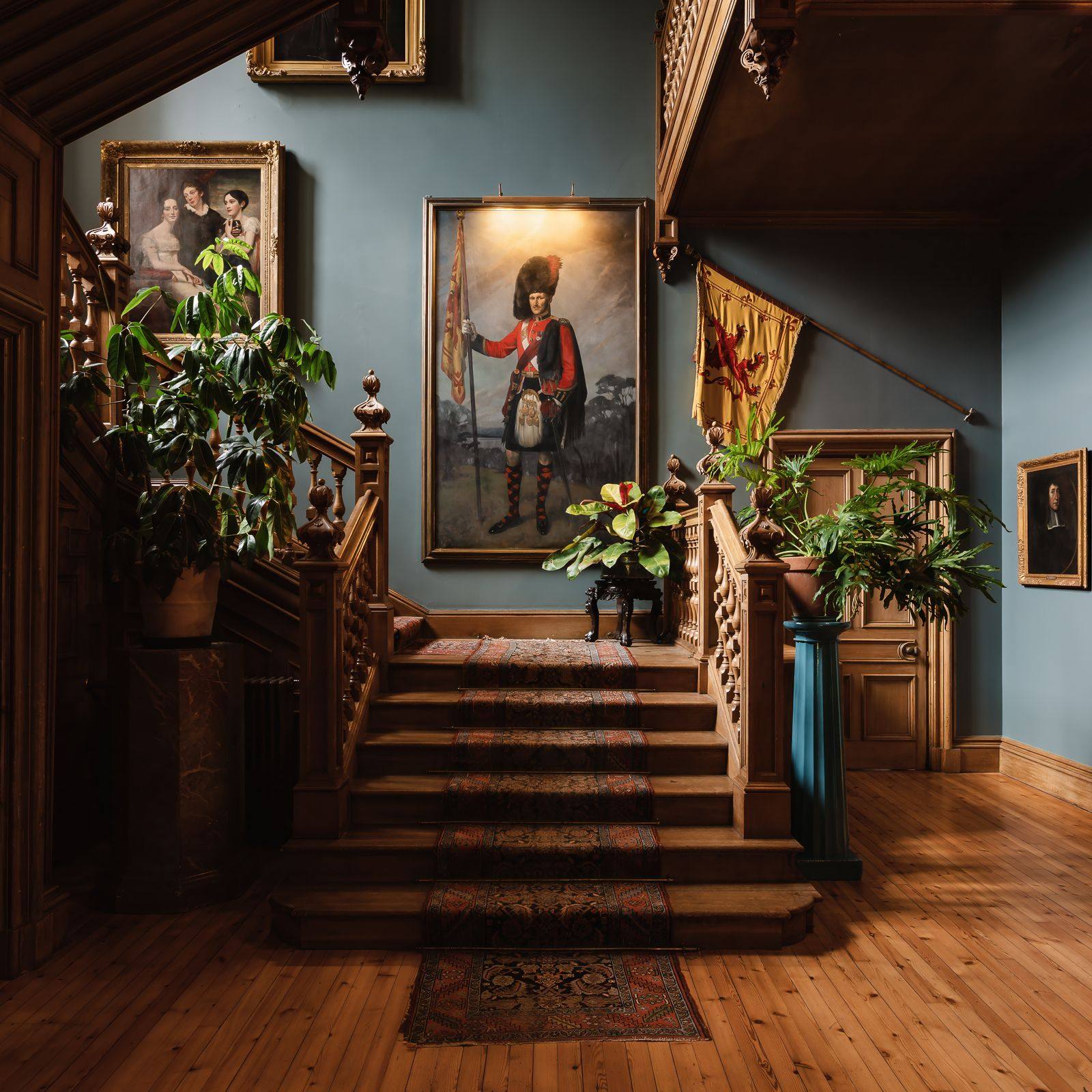 The staircase hall at Birkhill Castle, with a portrait of a Highland officer and the Lion Rampant flag of Scotland