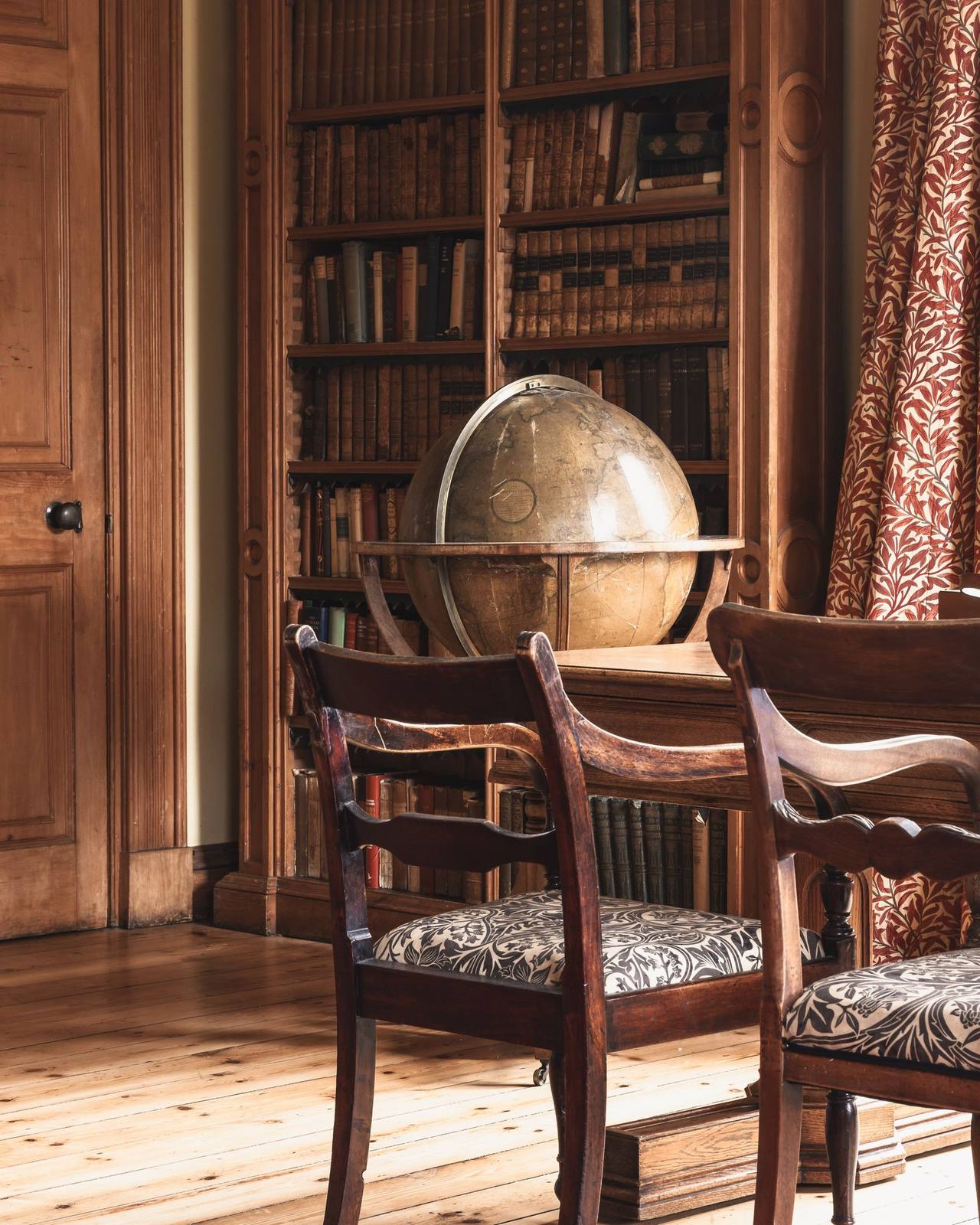 A close view of the library, an antique globe against the leather-bound collection