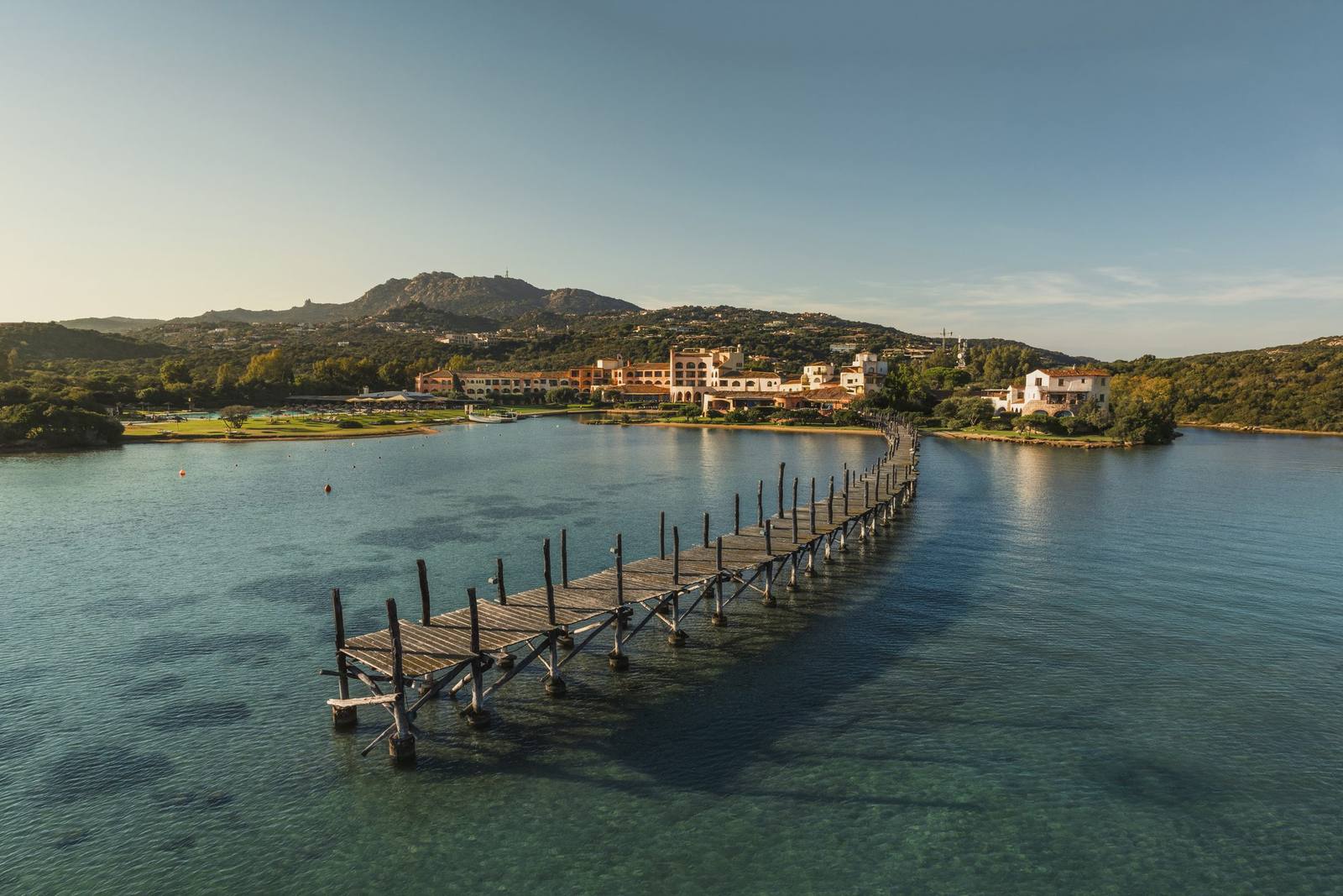 Aerial view of the long wooden jetty reaching into the turquoise bay in front of Hotel Cala di Volpe