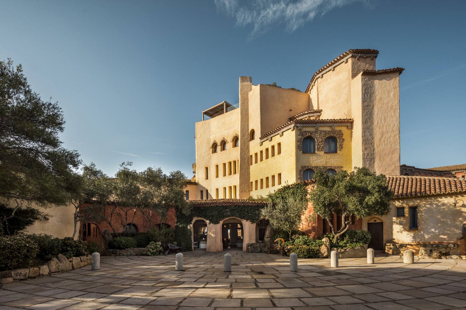 The terracotta-toned entrance tower of Hotel Cala di Volpe under a clear blue sky
