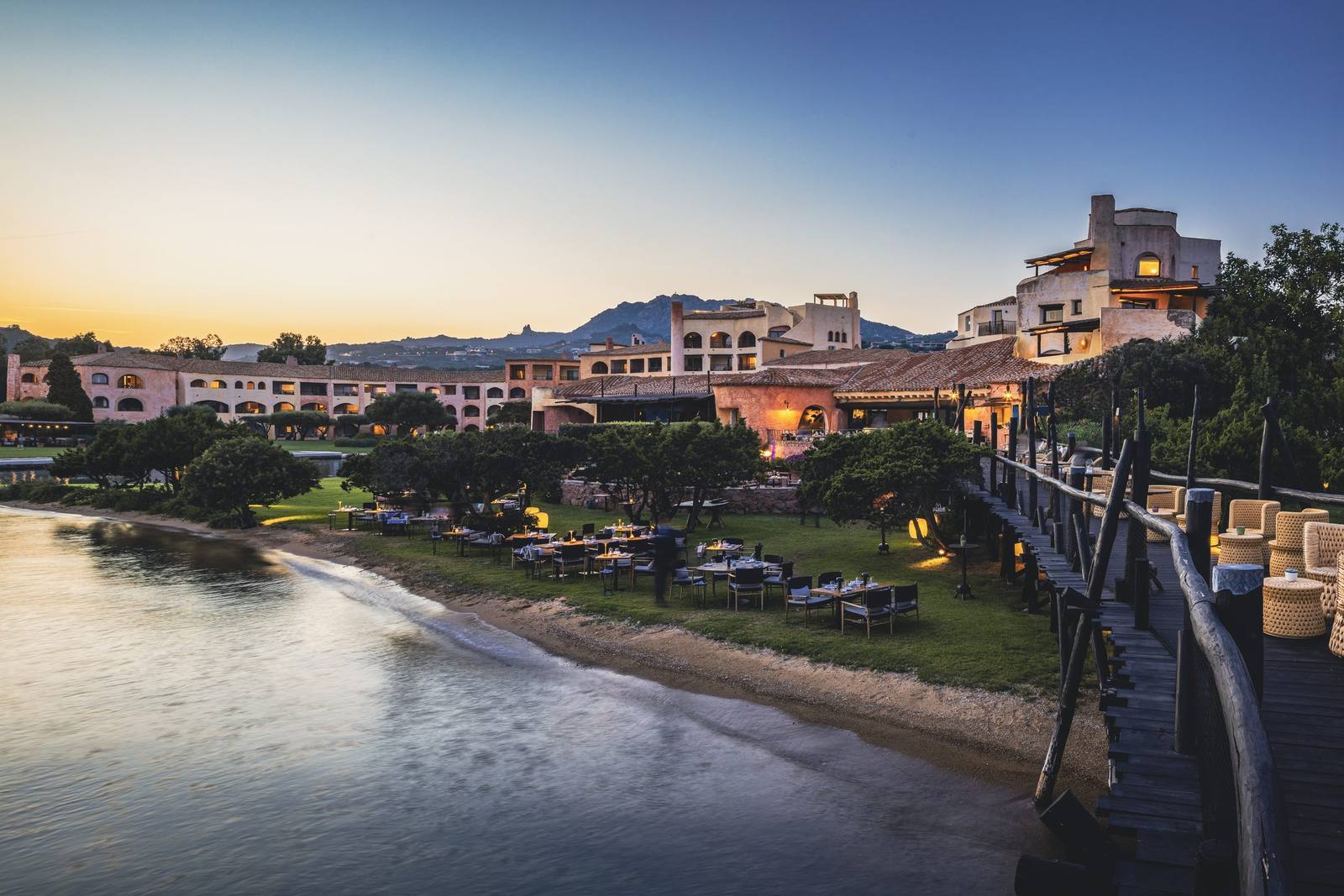 Matsuhisa at Cala di Volpe at sunset, tables along the shoreline and the hotel glowing beyond
