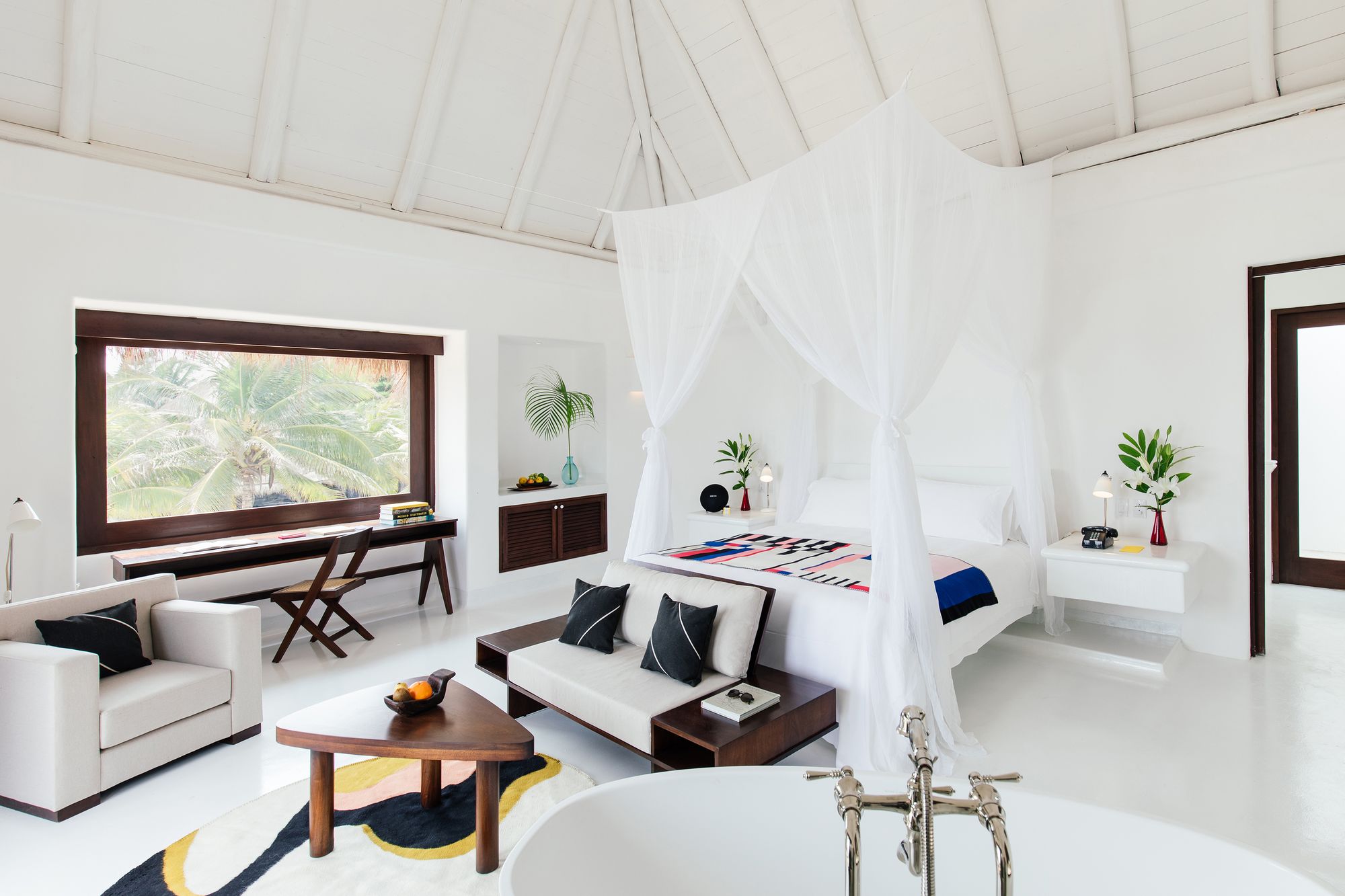 White canopy bed and sitting area in a suite at Hotel Esencia