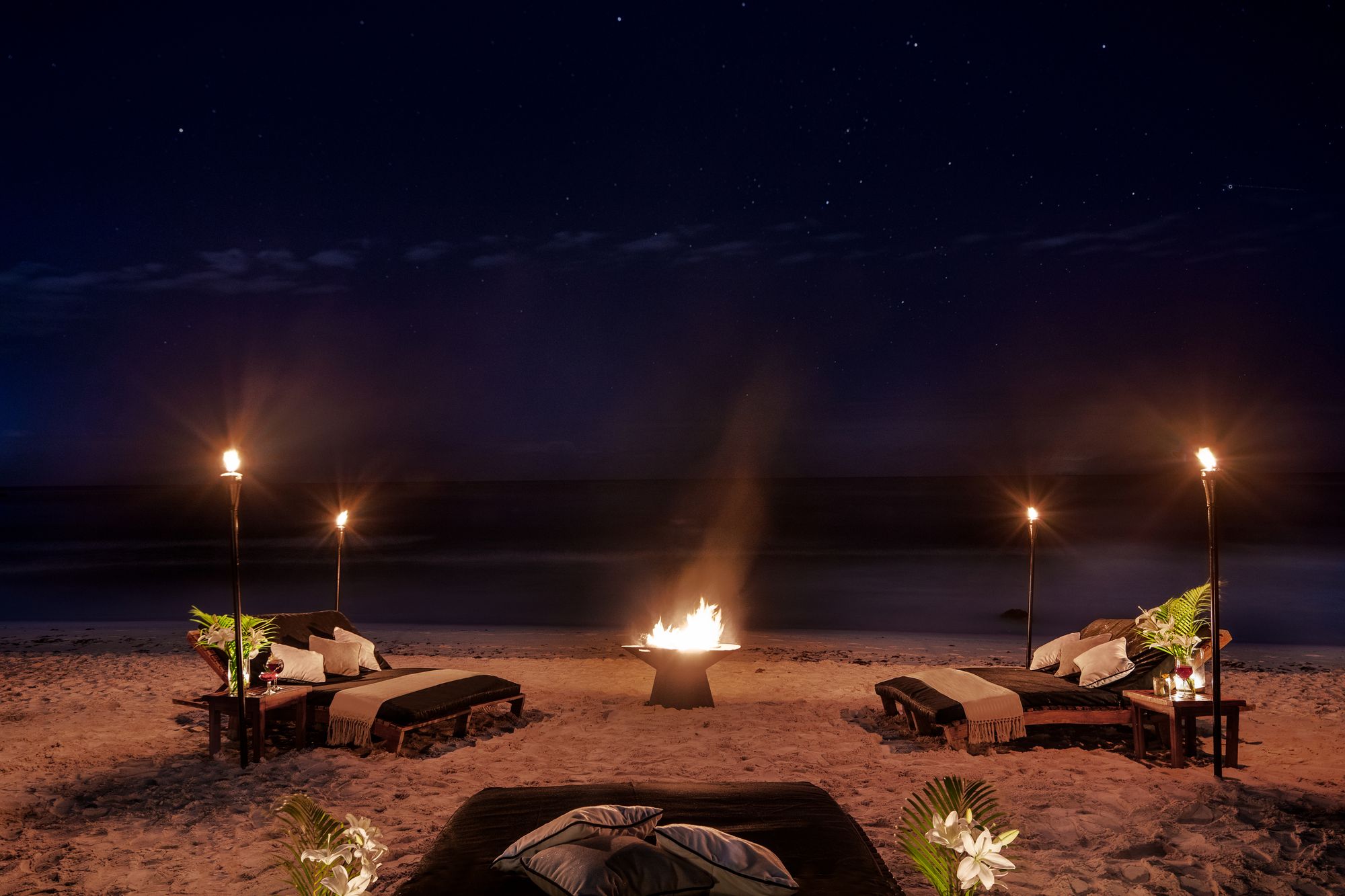 Torch-lit bonfire on the beach at night at Hotel Esencia