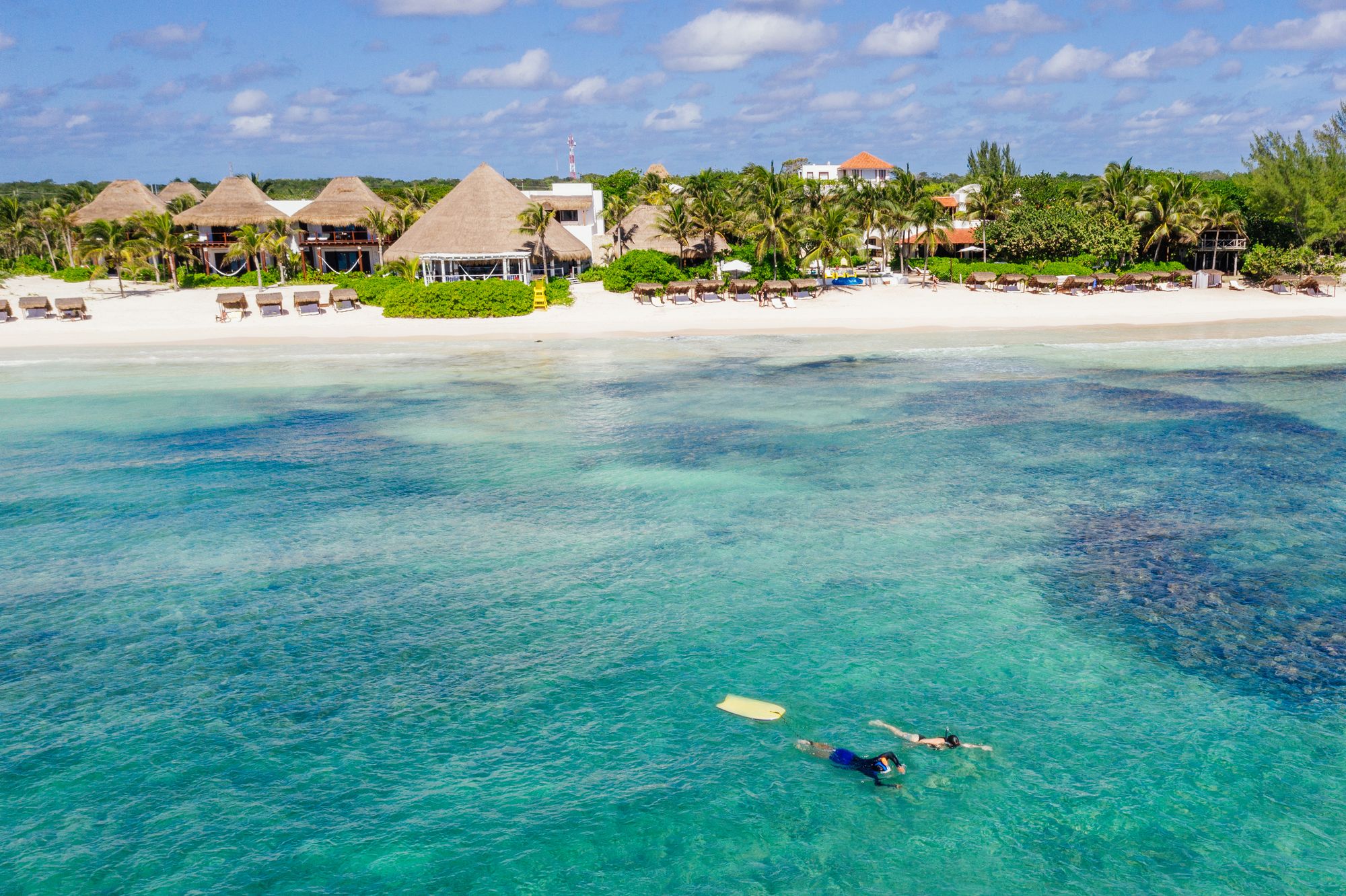 Snorkellers in clear turquoise water off the beach at Hotel Esencia
