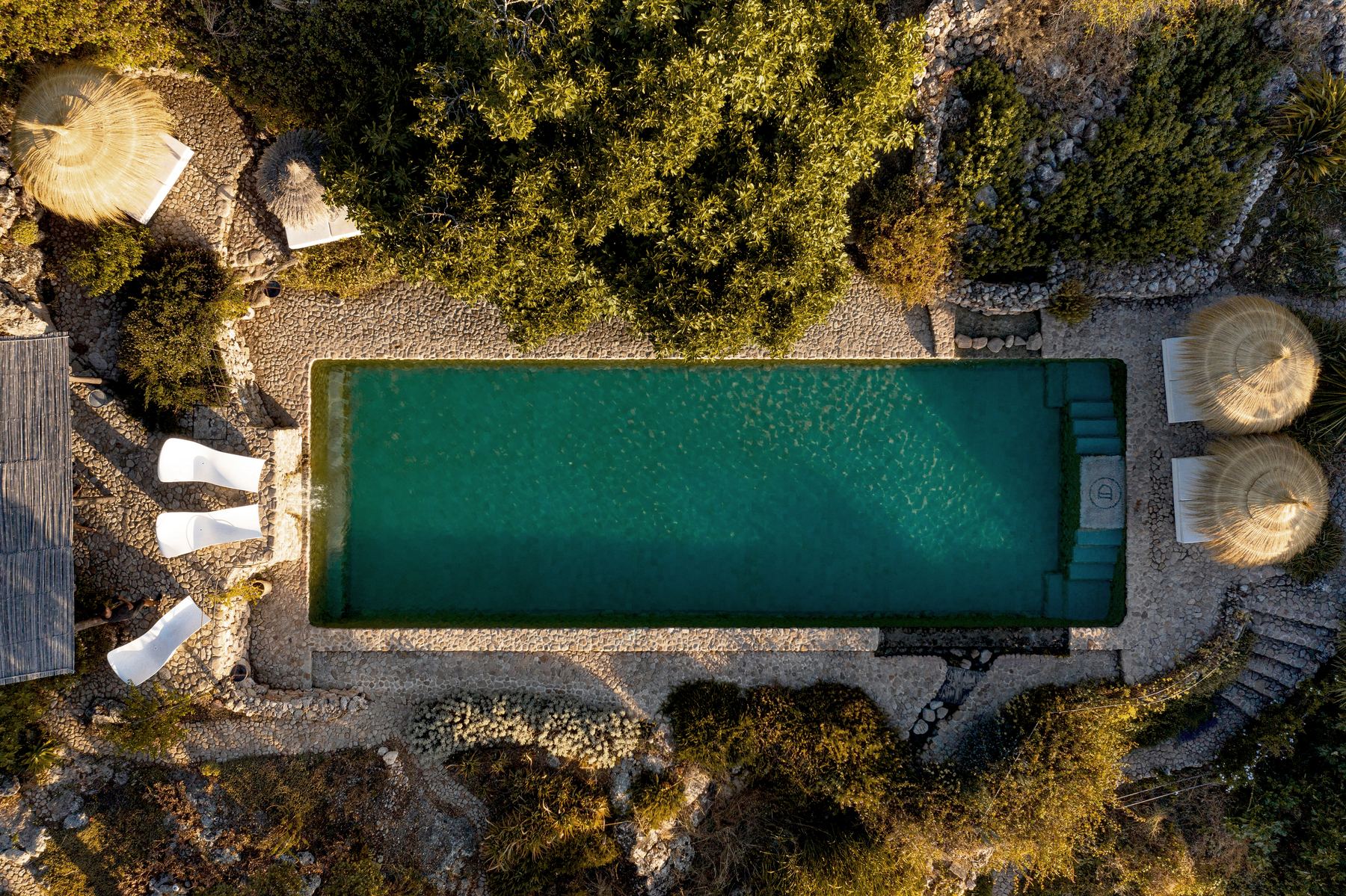 Aerial view of a long spring-fed pool surrounded by gardens and parasols
