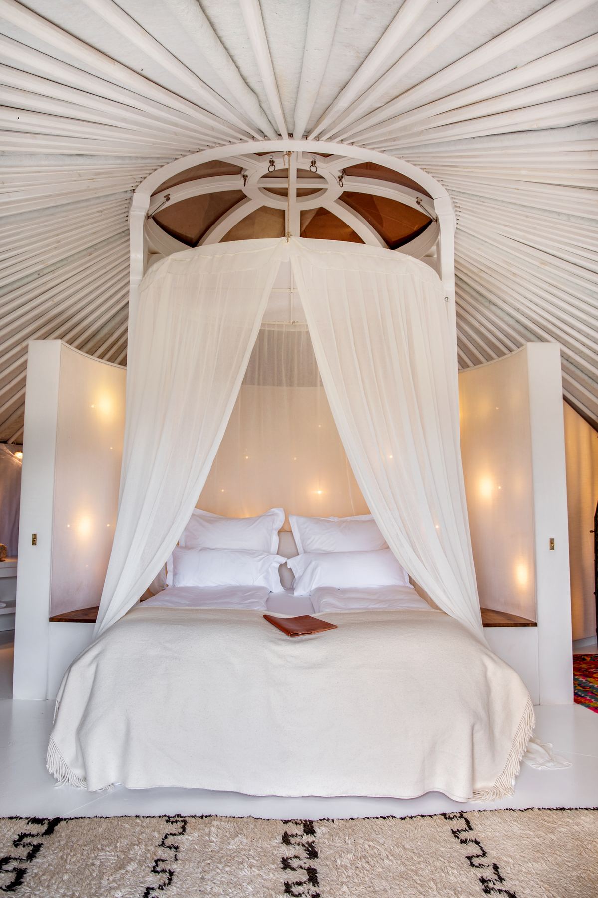 A canopied bed draped in white gauze inside a yurt