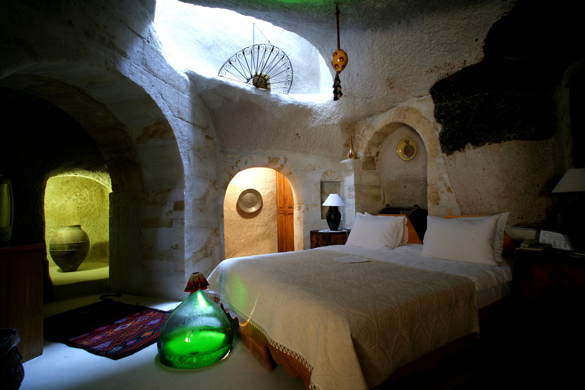 Cave bedroom with arched stone walls, antique vases and Turkish textiles at Museum Hotel, Uçhisar