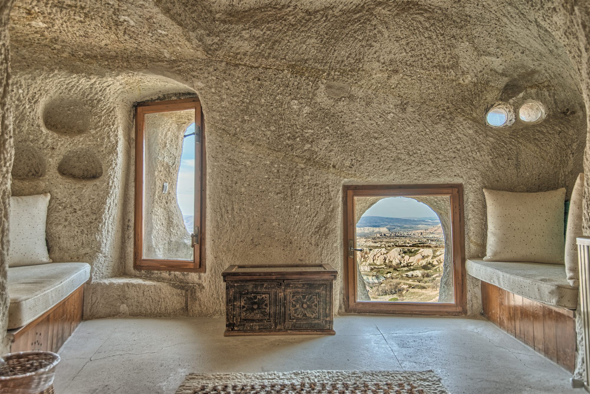 Cave room with carved stone seating and a small window looking out over the Cappadocia valleys