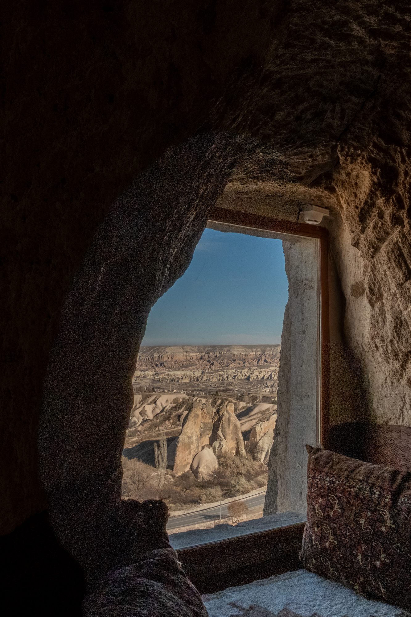 View of Cappadocia's fairy chimneys framed by a window cut into the cave wall at Museum Hotel