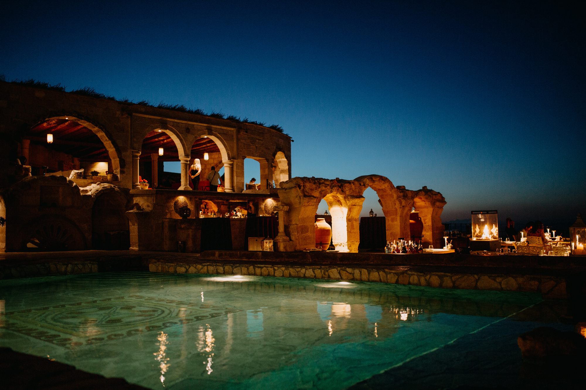 Ruined stone arches lit at dusk beside the pool at Museum Hotel, Uçhisar