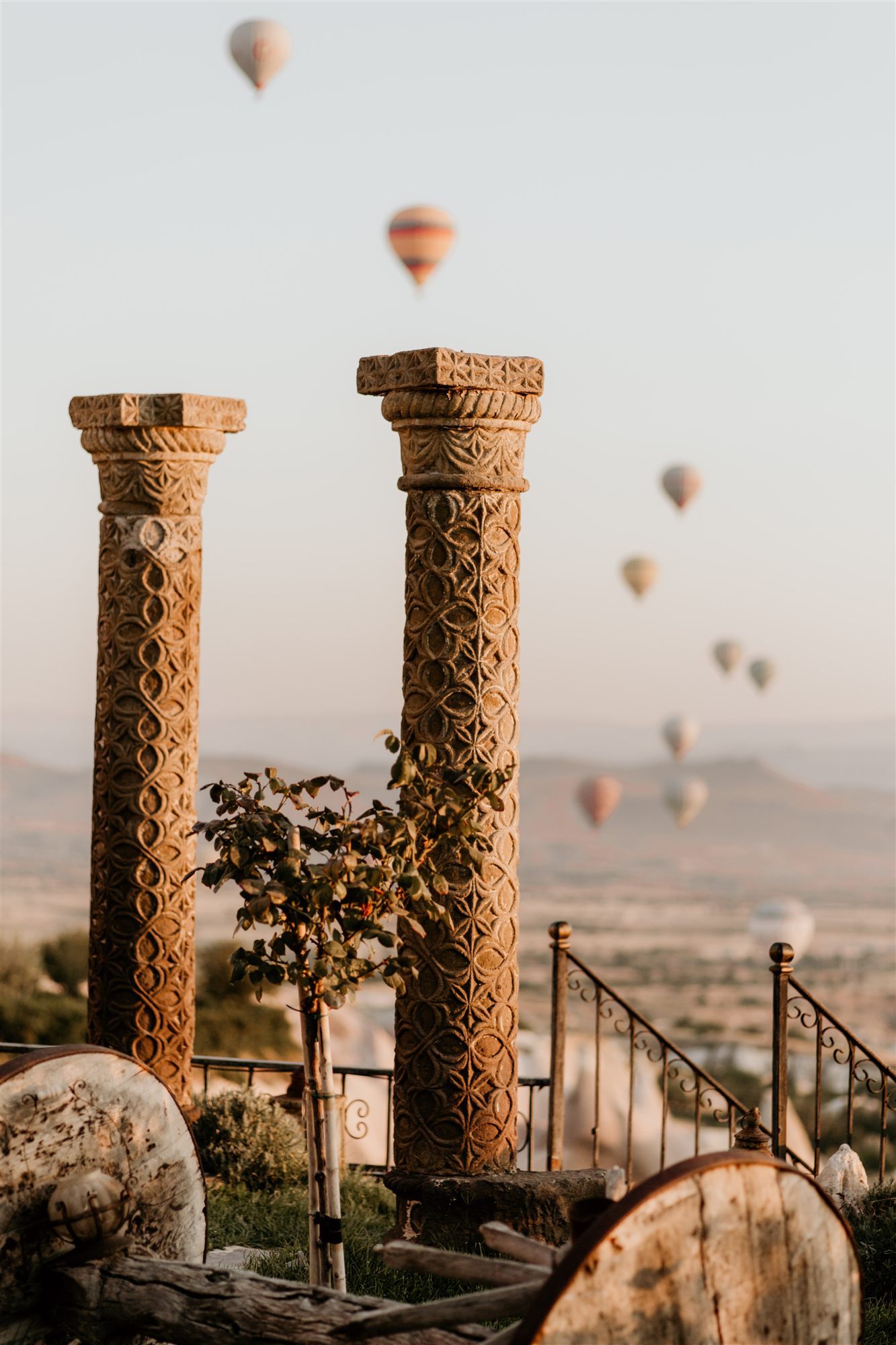 Two ancient Roman columns in the garden of Museum Hotel with hot air balloons over Cappadocia