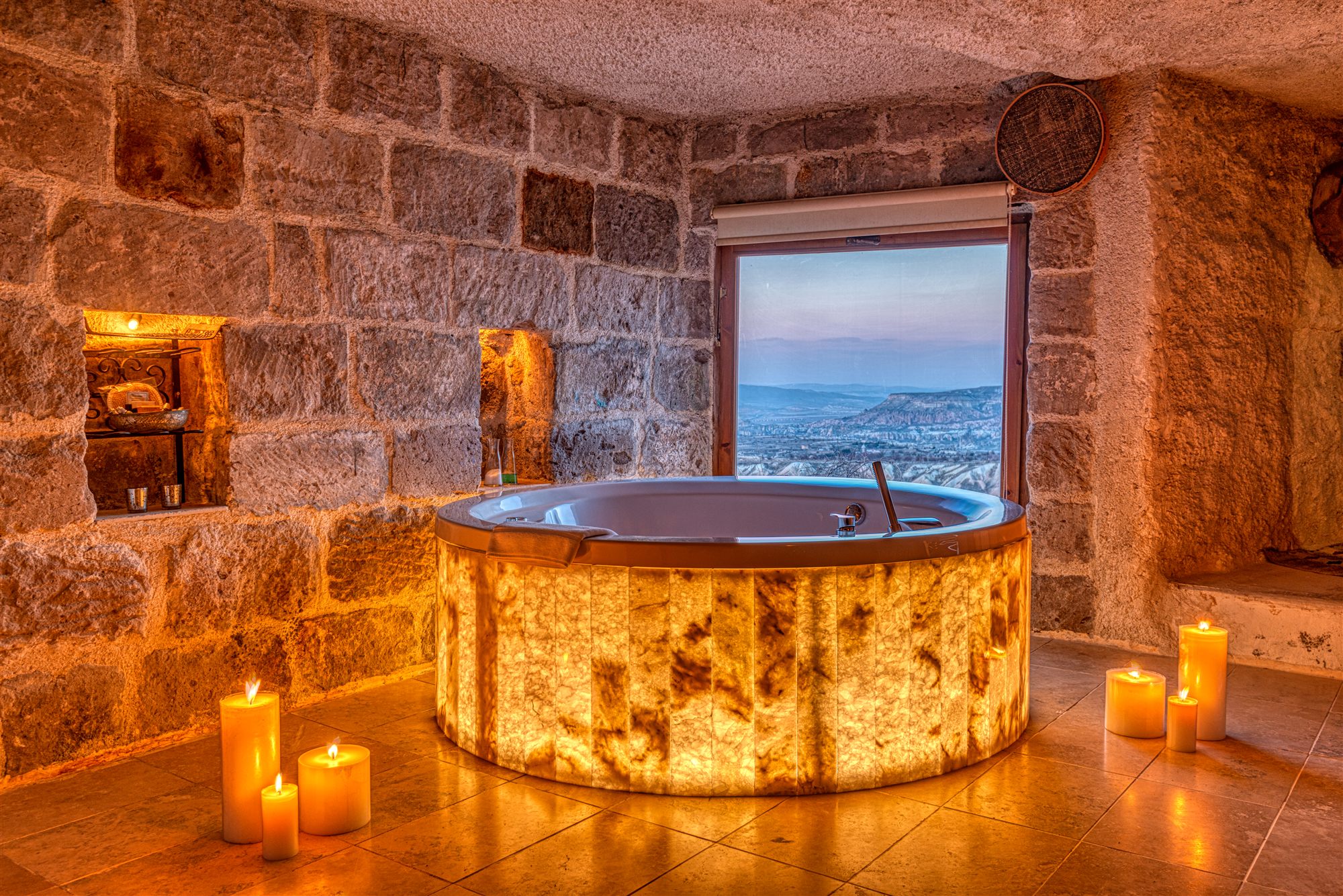 Candlelit illuminated onyx bathtub facing a window over the Cappadocia valley at Museum Hotel