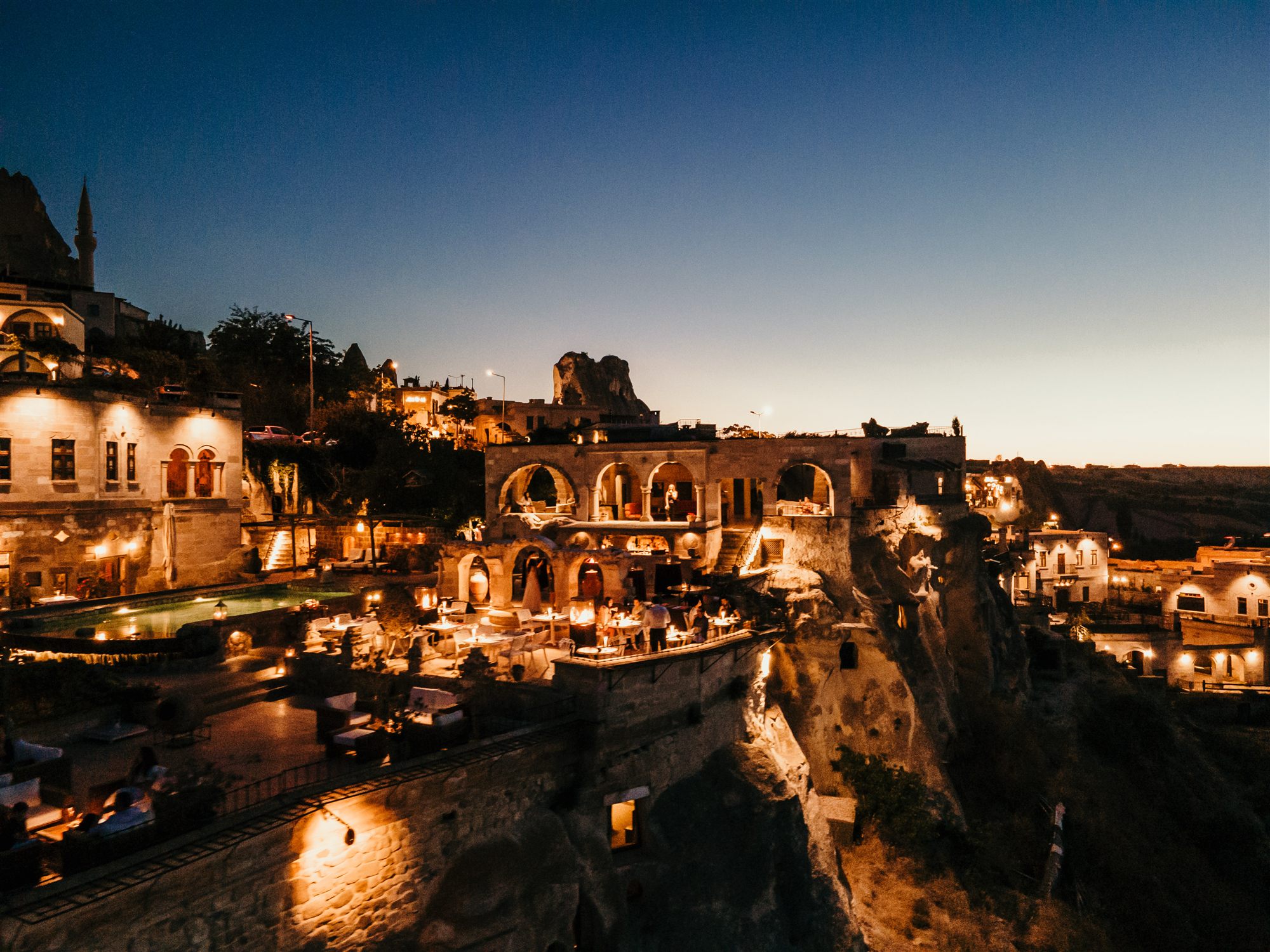 Museum Hotel and the cave houses of Uçhisar village lit at twilight on the cliffs of Cappadocia