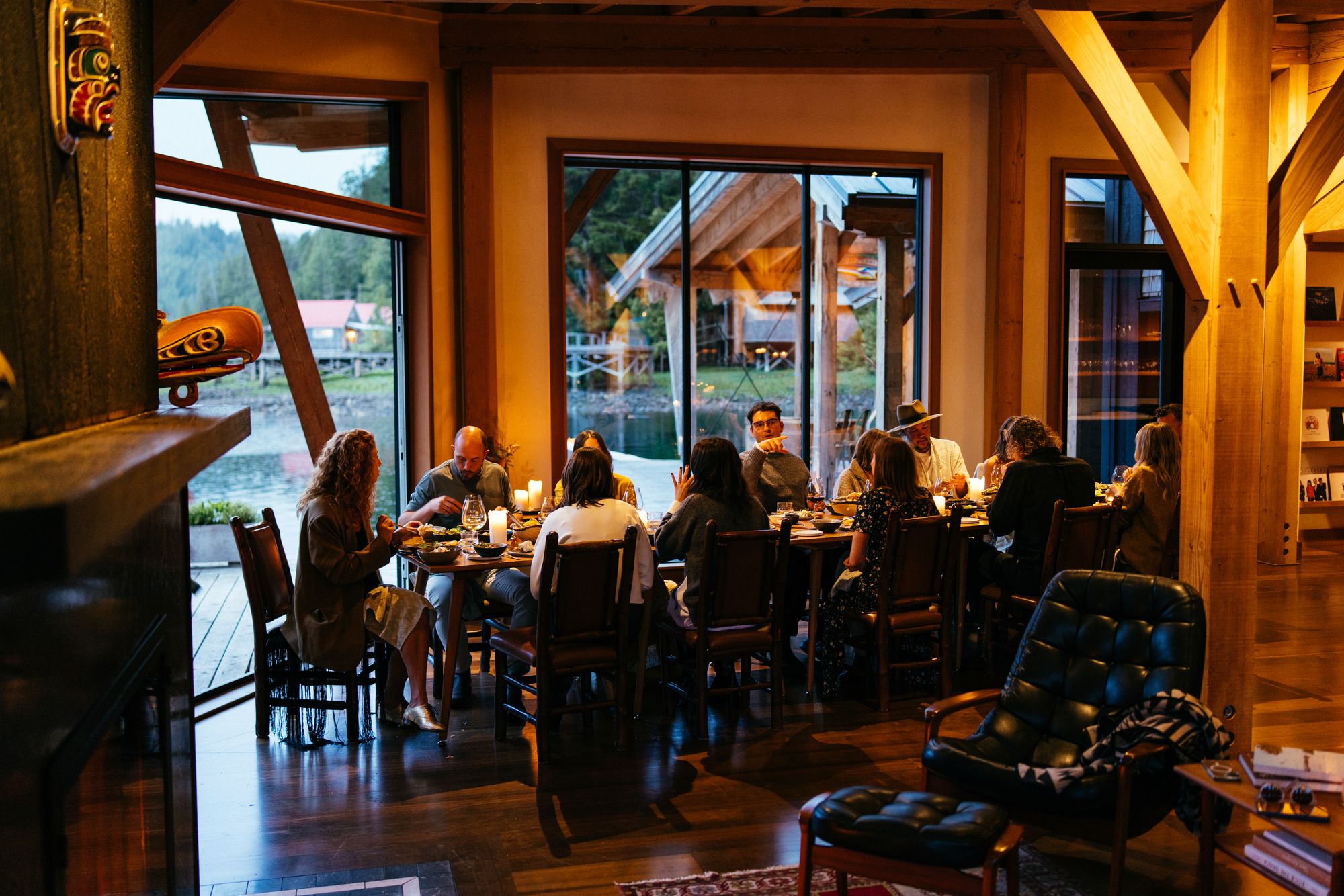 Guests dining together in the warm, timber-framed dining room at Nimmo Bay