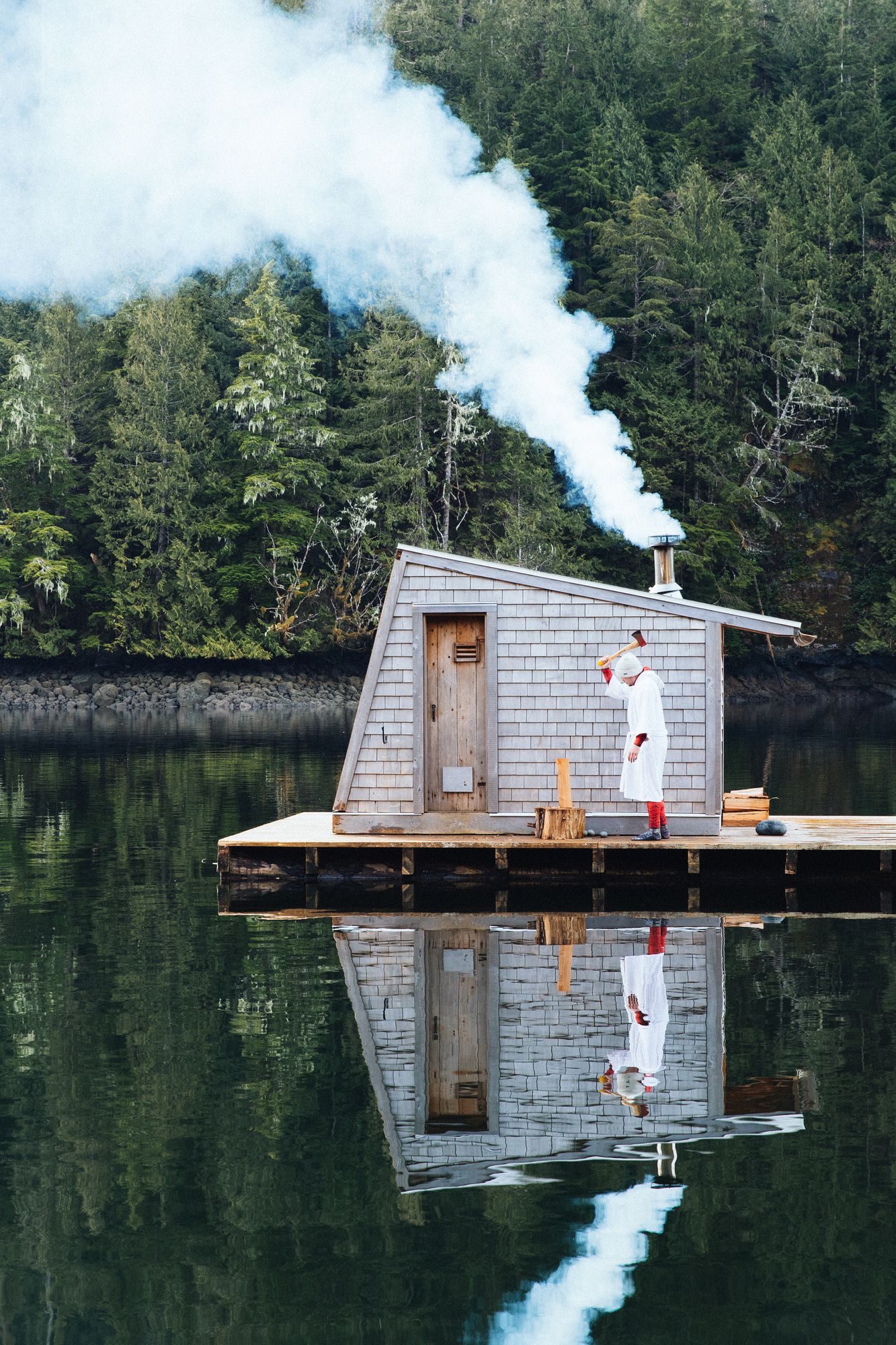 Floating sauna with smoke rising from its chimney on the calm water at Nimmo Bay