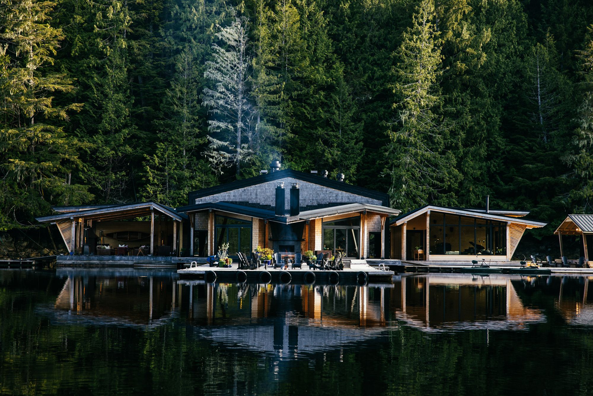 The Little River restaurant and lounge at Nimmo Bay reflected in still water below the rainforest