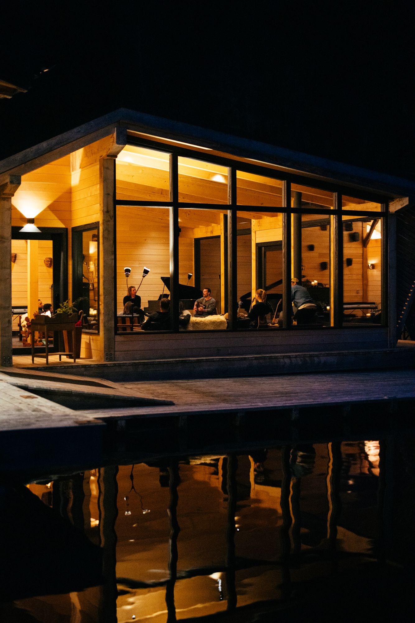 The Melody Lounge at Nimmo Bay glowing at night, reflected in the dark water