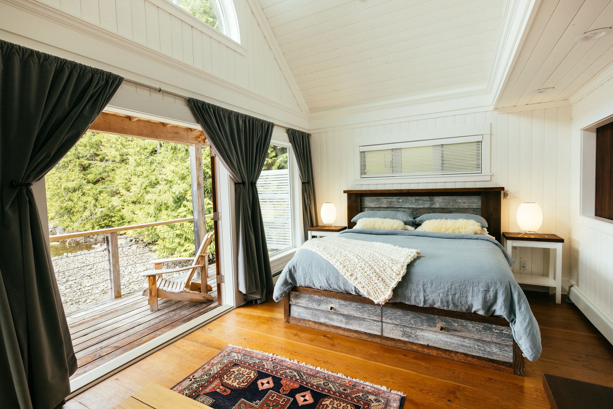 Waterfront cabin bedroom at Nimmo Bay with open doors onto a deck above the water
