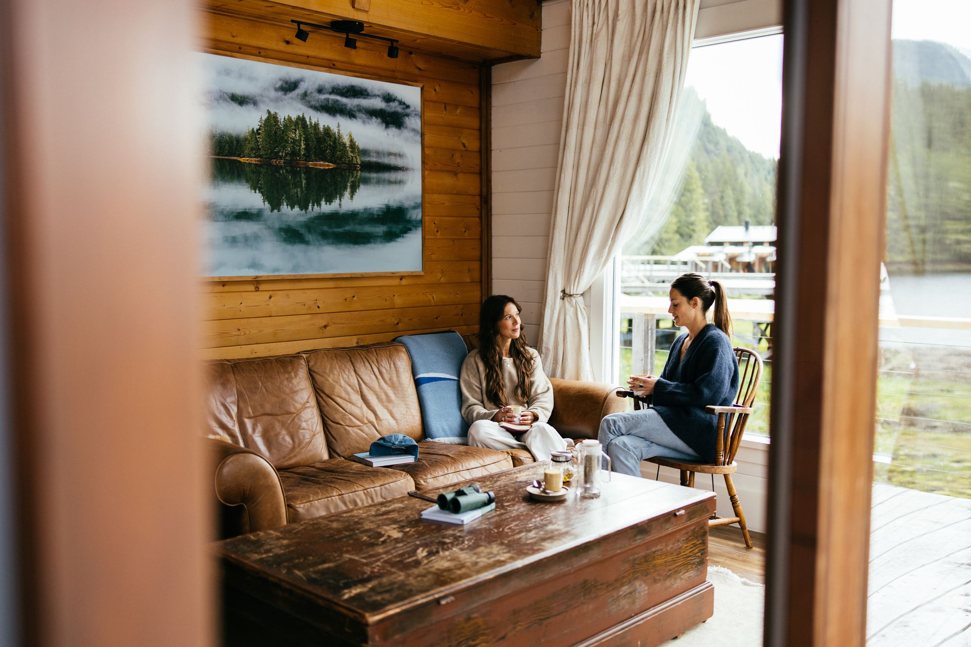 Guests relaxing in the lounge of a waterfront cabin at Nimmo Bay