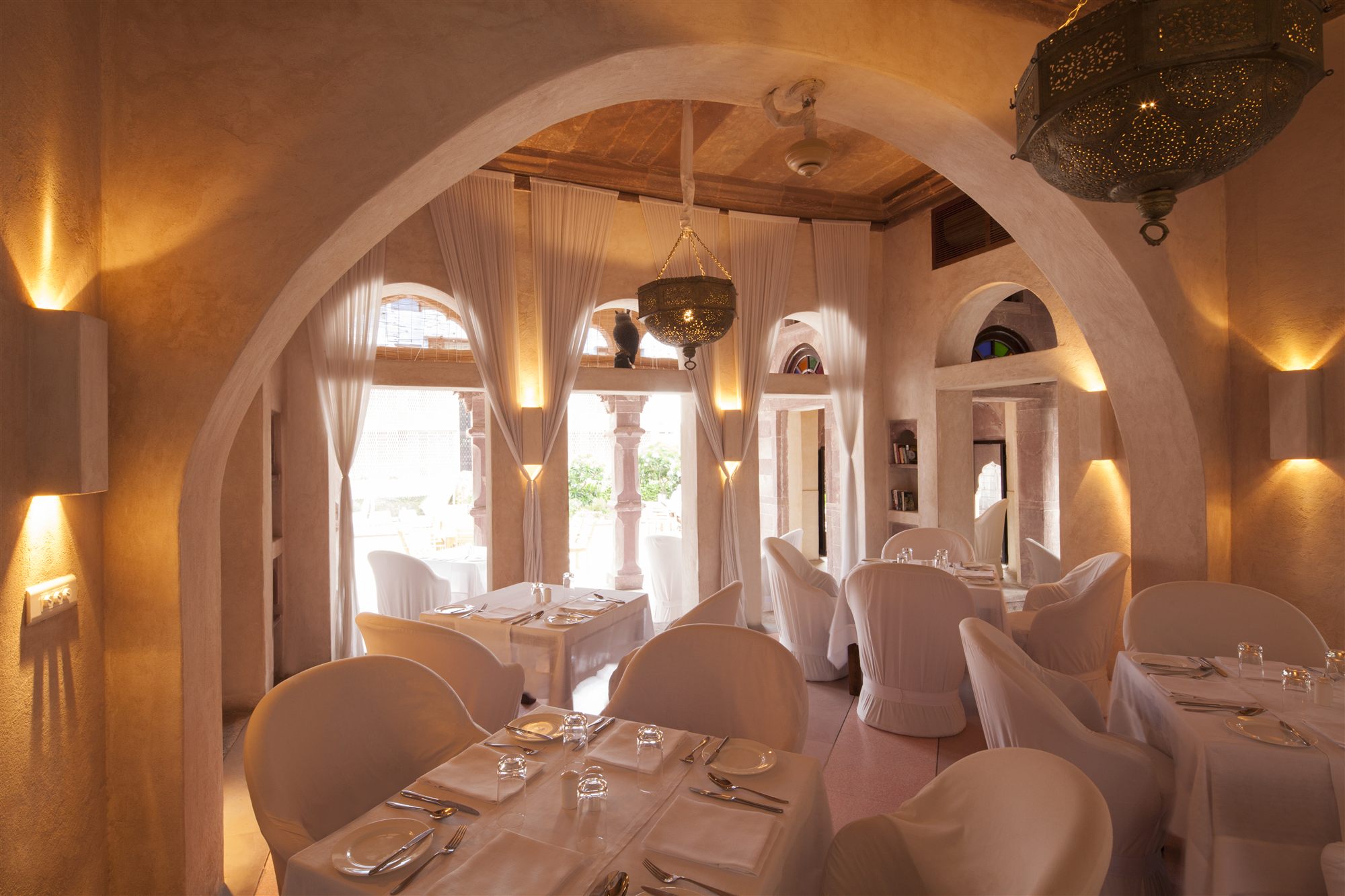 Baradari restaurant at RAAS Jodhpur, an arched 18th-century pillared hall with white dining chairs