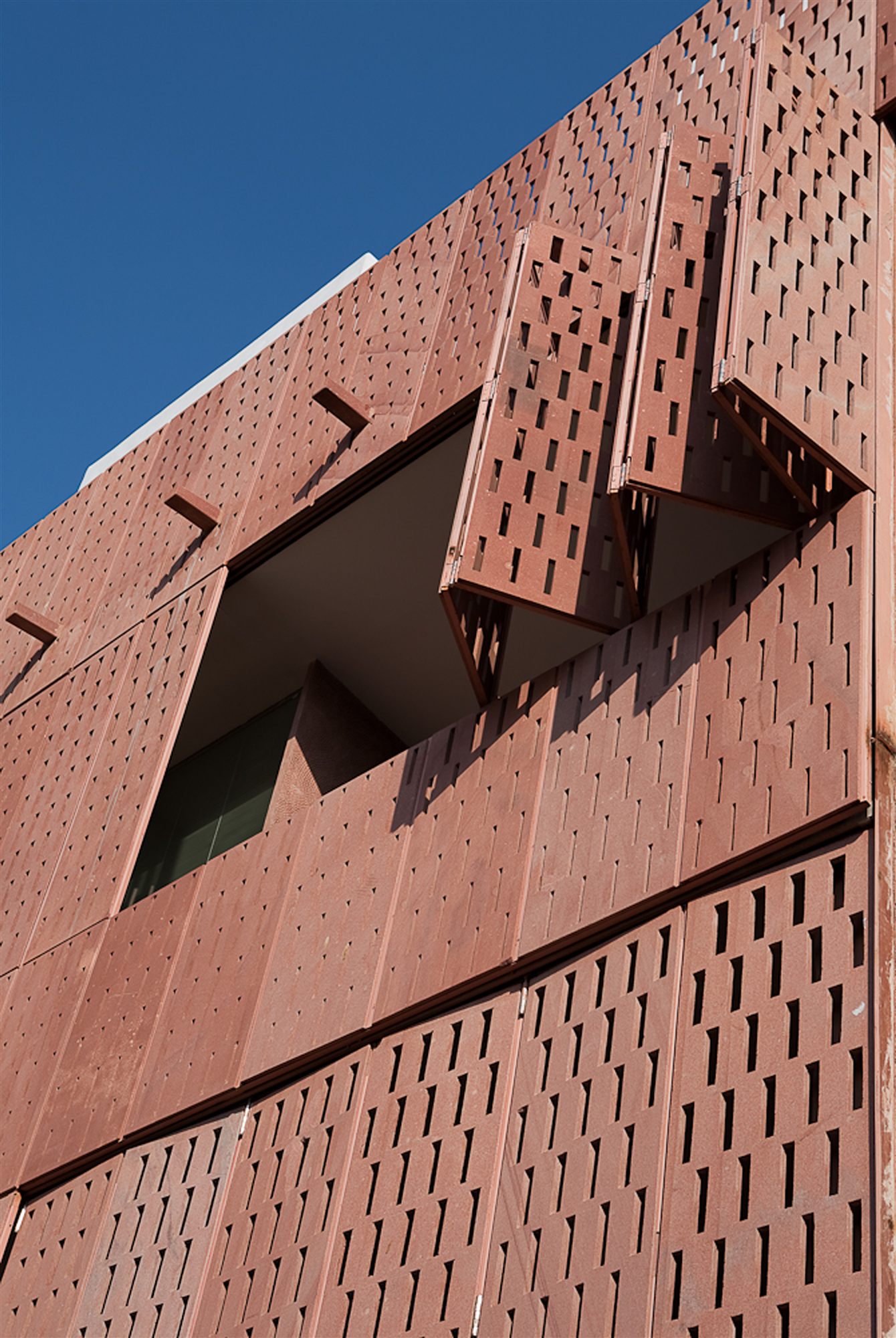 Folding hand-cut sandstone lattice shutters on the facade of RAAS Jodhpur against a blue sky