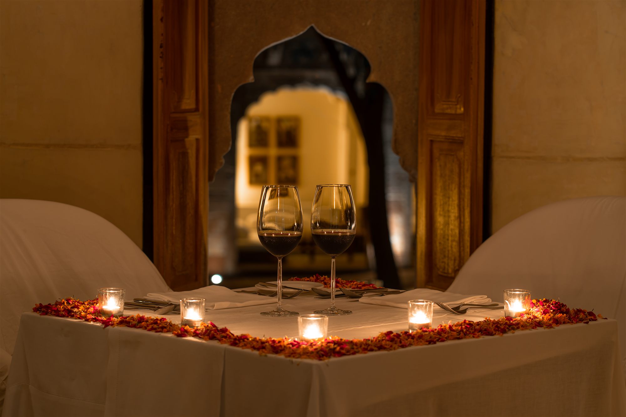 Candlelit private dinner for two with rose petals under a carved arch at RAAS Jodhpur