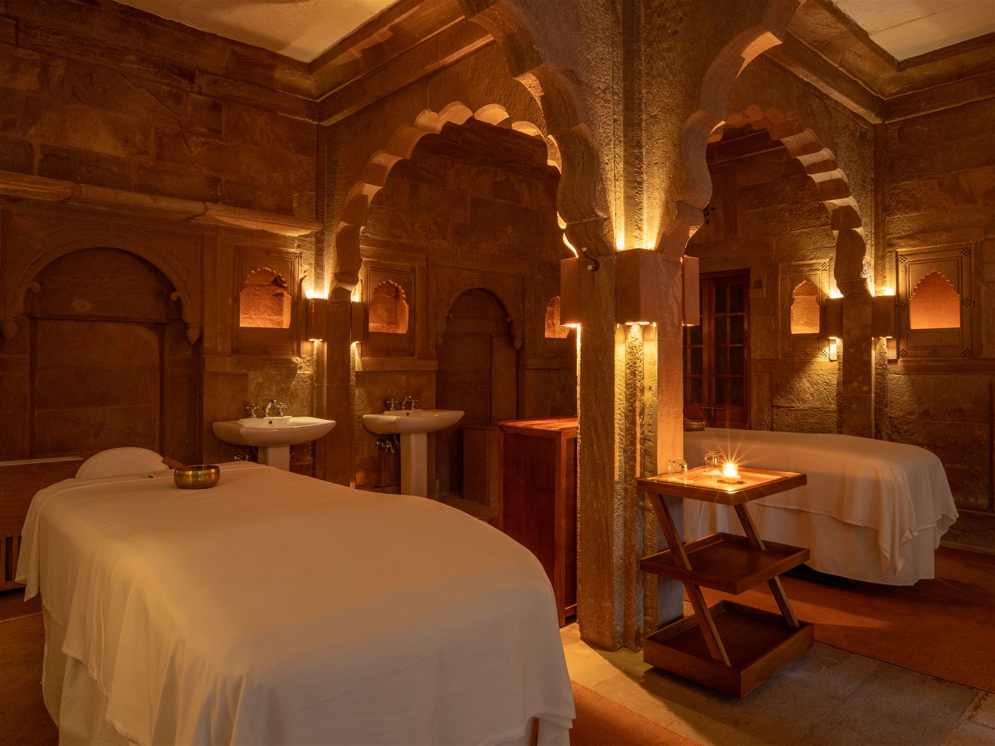 Candlelit spa treatment room under carved sandstone arches in the heritage haveli at RAAS Jodhpur