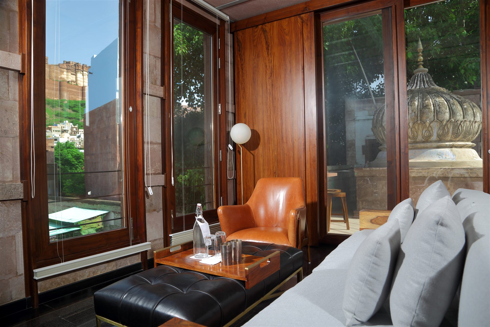 Stepwell Suite sitting area at RAAS Jodhpur with leather chair and floor-to-ceiling windows toward Mehrangarh Fort