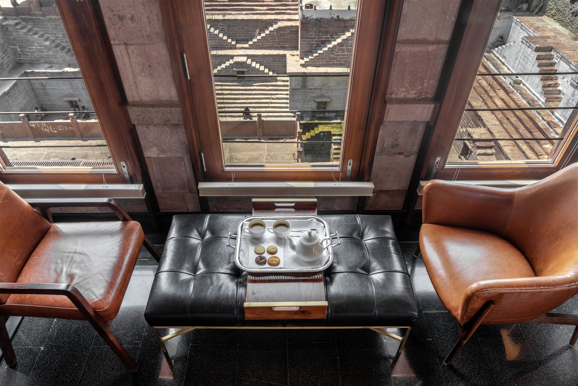 Leather armchairs at a window overlooking the steps of Toorji ka Jhalra stepwell from the Stepwell Suite, RAAS Jodhpur