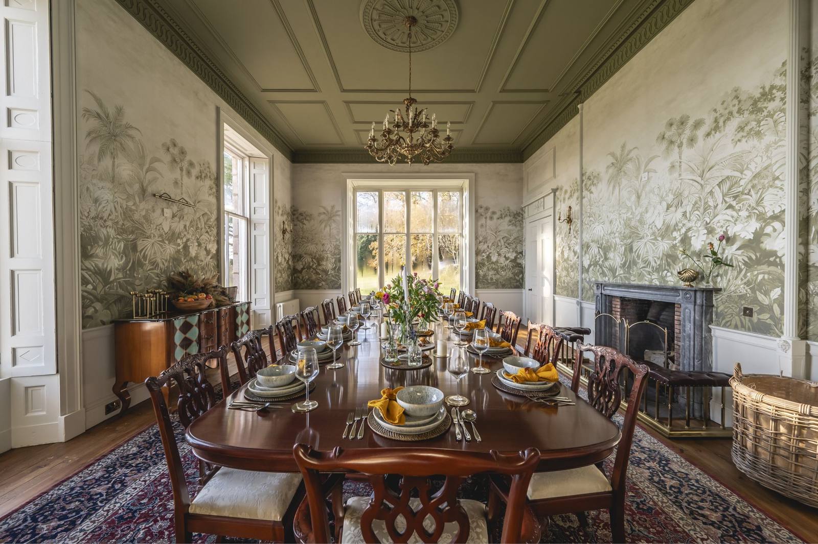 The dining room at Manar House, hand-painted wallpaper and a long laid table