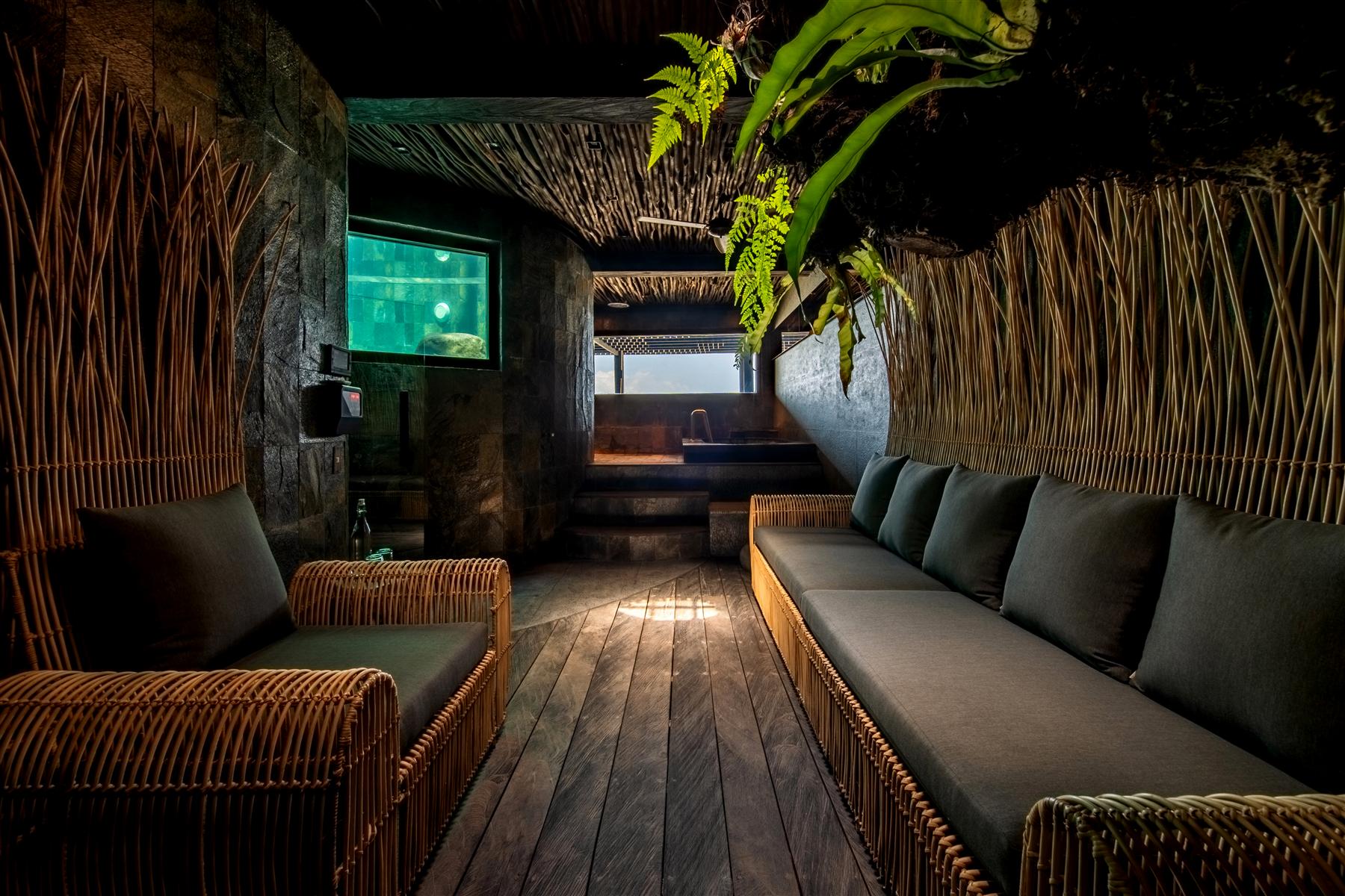 Rattan sofas and bamboo walls in a dim lounge at The Seed resort in Candidasa, Bali