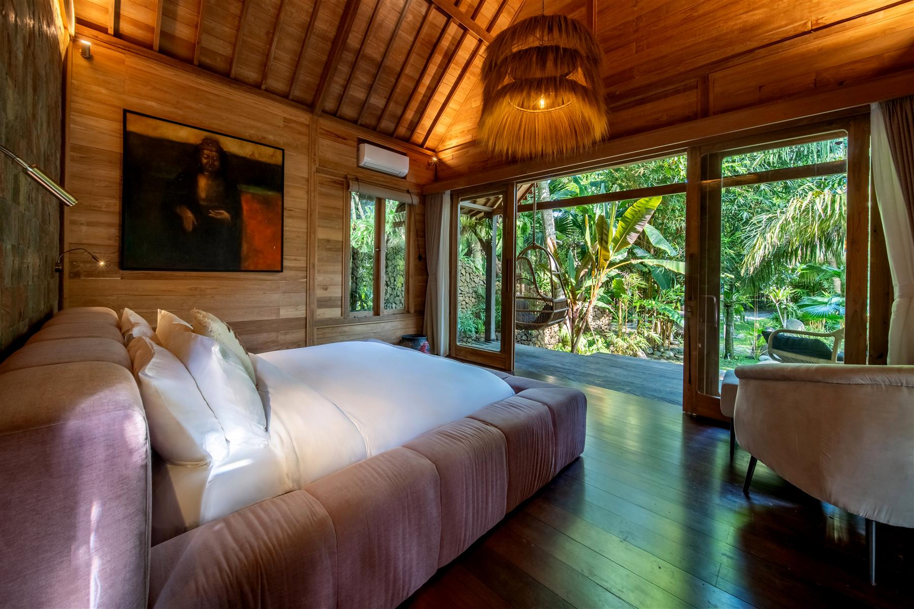 Wood-paneled bedroom at The Seed Bali with king bed, vaulted ceiling, and jungle views through glass doors