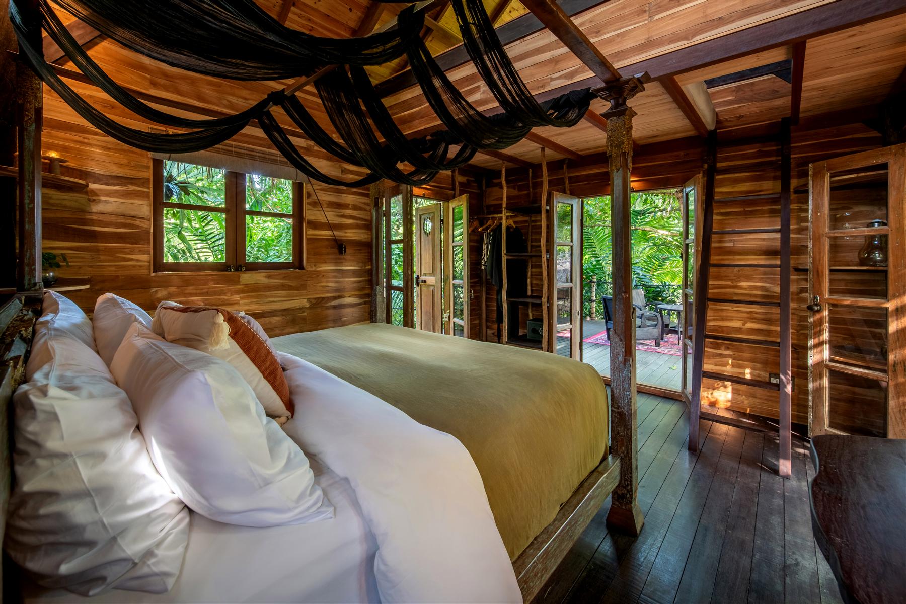 Wooden bedroom at The Seed Bali with draped black fabric ceiling and garden views