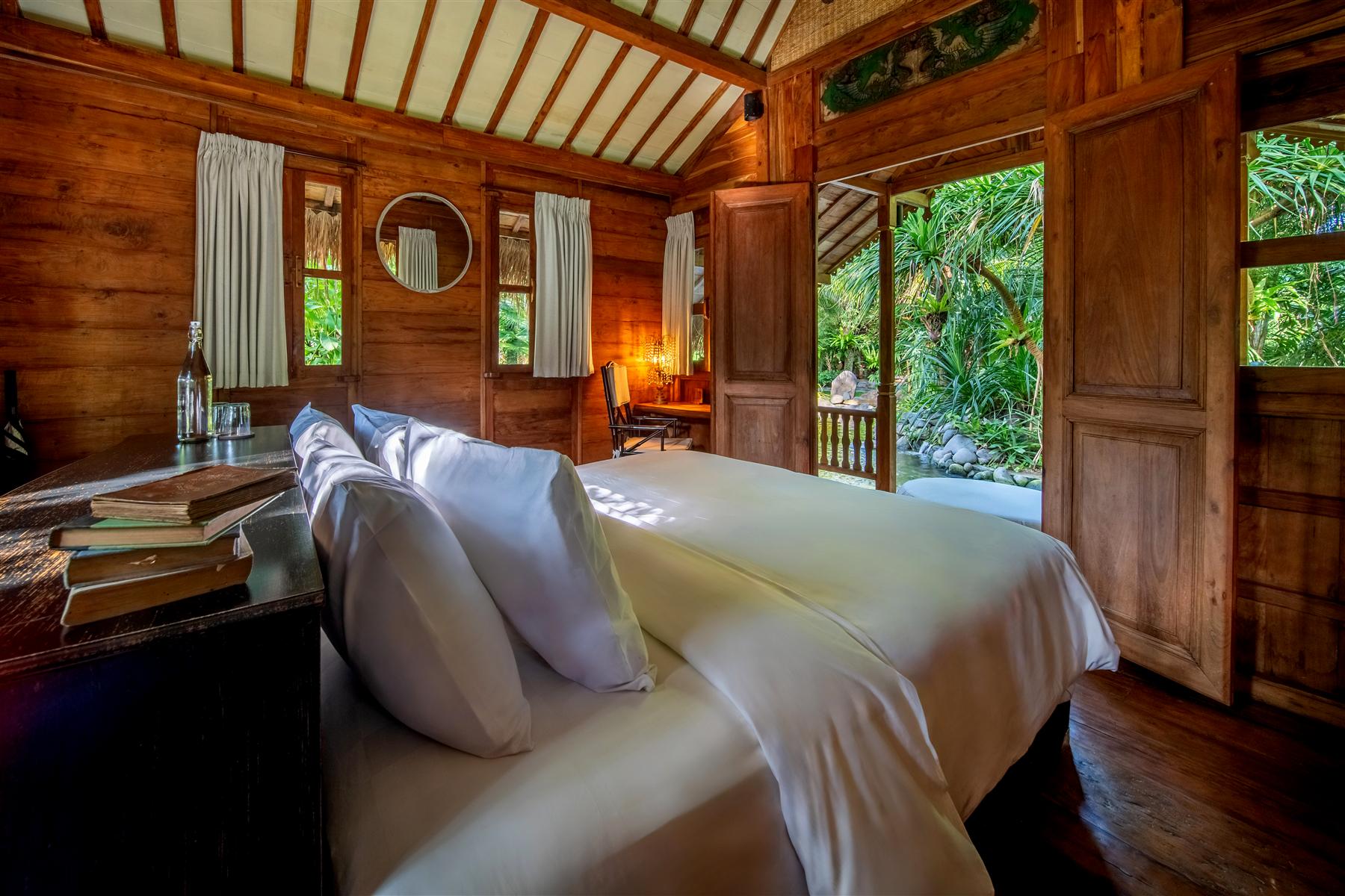Teakwood bedroom suite at The Seed resort in Candidasa, Bali, with white linens and garden views